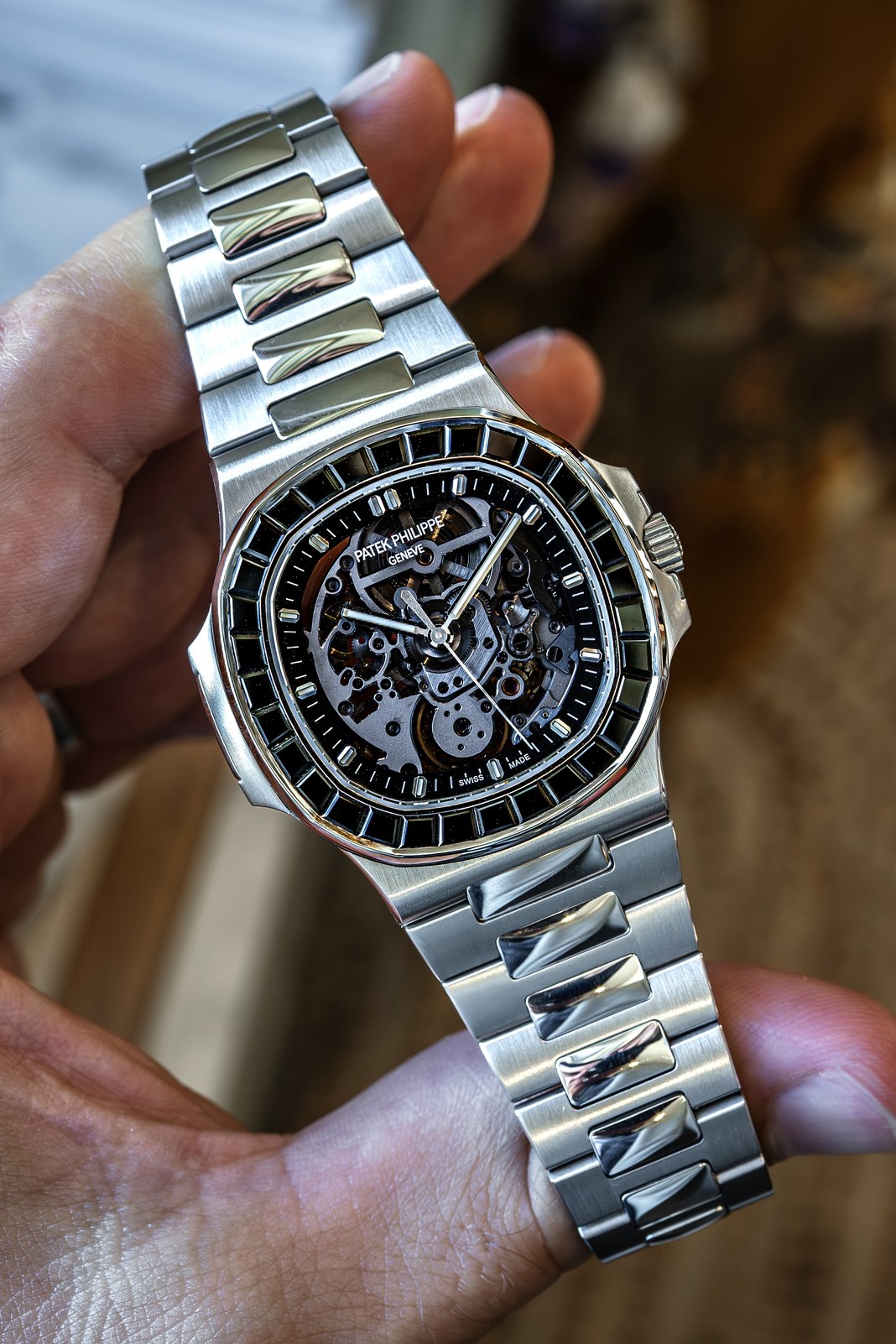 The Artisans de Genève Black Stone, a client's Patek Philippe 5711A with a black spinel bezel and skeletonised dial, held vertically in one hand