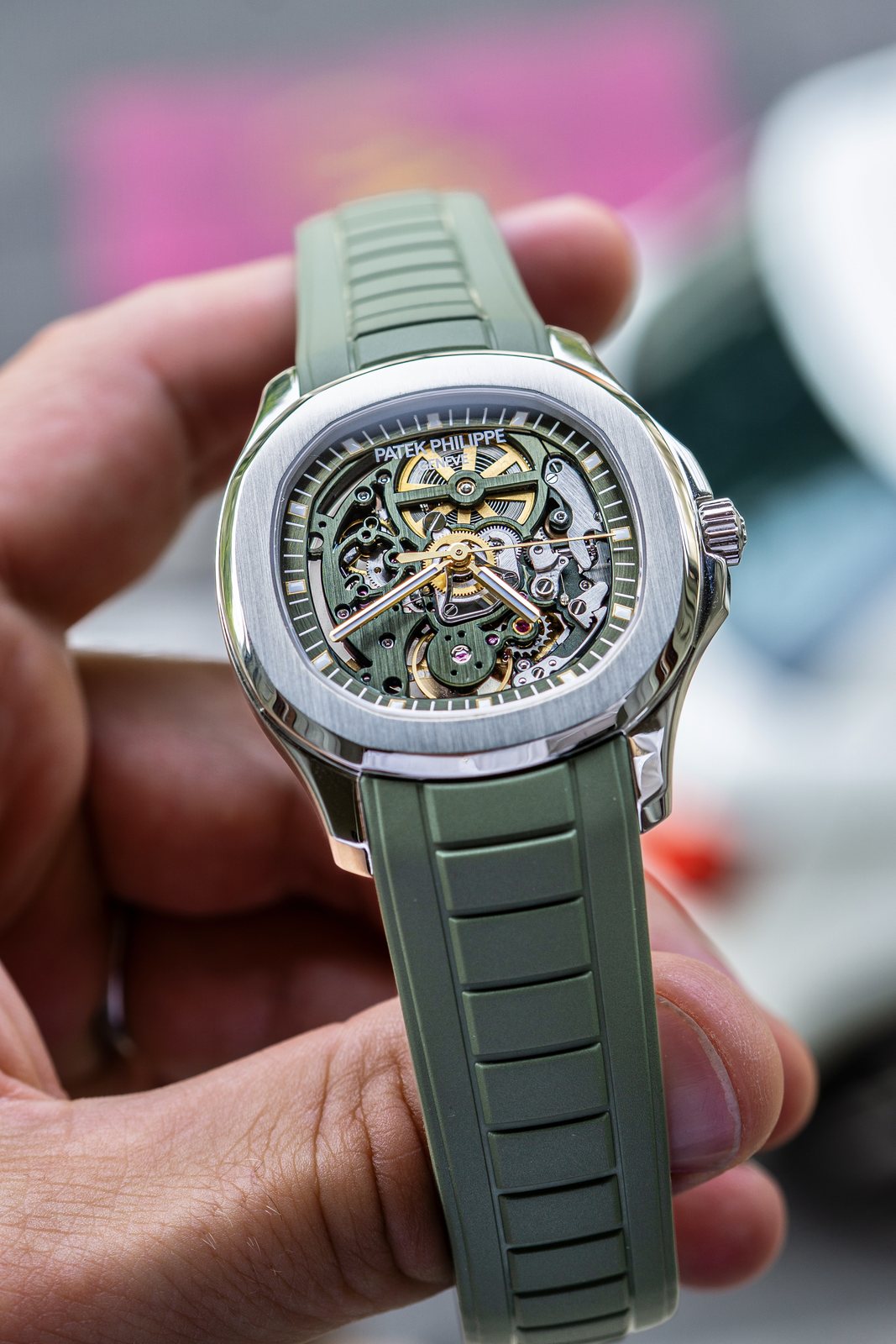 A skeletonised Patek Philippe Aquanaut held in one hand, its movement finished in green, on a green rubber strap