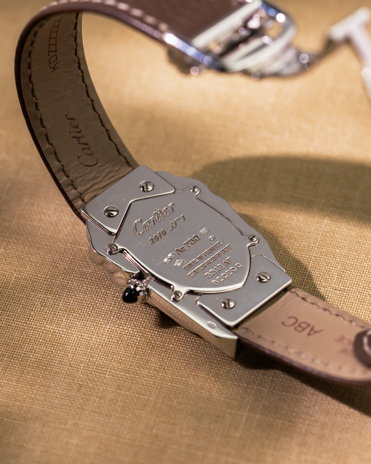 The case back of the Cheich, engraved Cartier 2010 No 1 with the gold mark and case numbers, the strap lining signed beside it