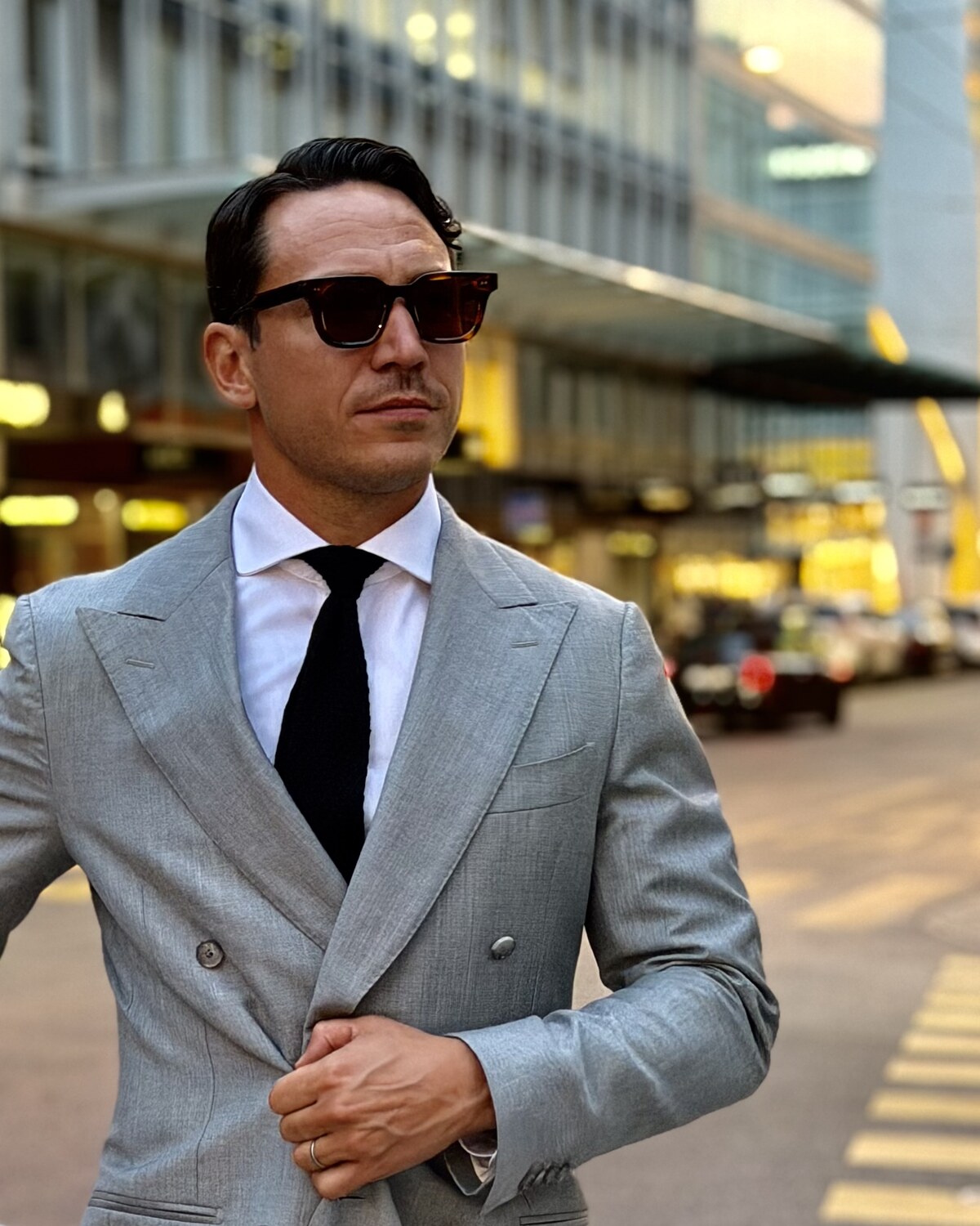 Jimmy Heneidy in a grey double-breasted suit and dark sunglasses on a city street