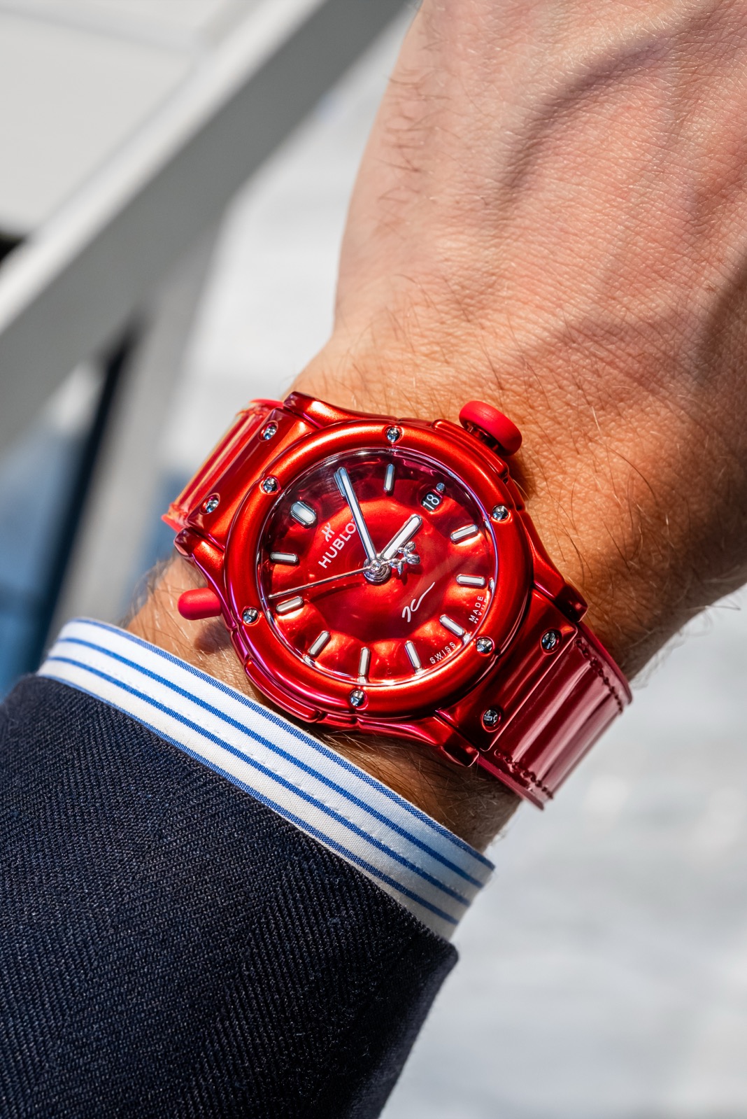 Red Hublot watch on a wrist, with rounded case forms, a small Balloon Dog at the centre of the hands and a signature on the dial