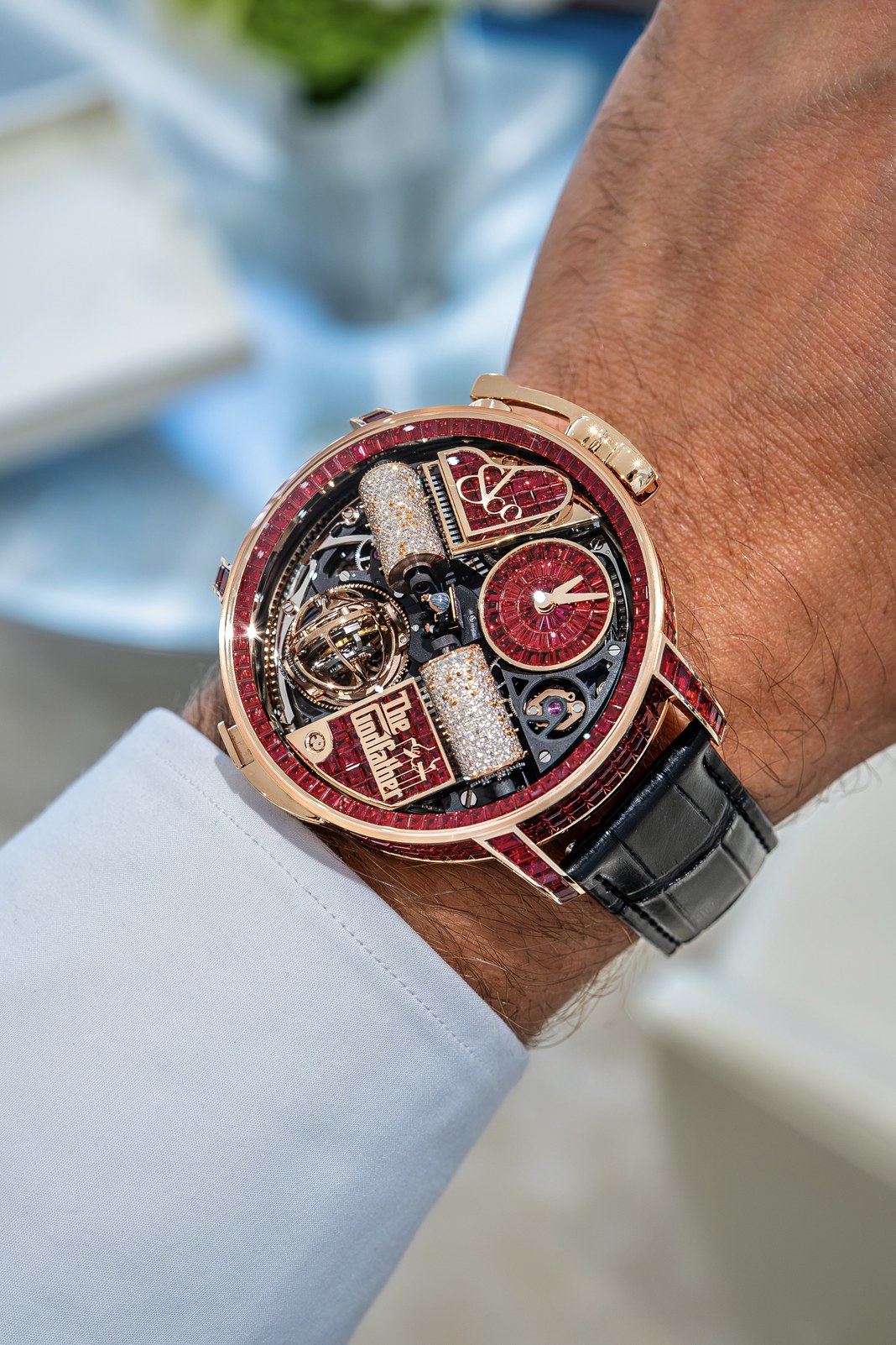 Opera Godfather Baguette on a wrist with a white cuff, showing the violin-shaped crank and red-sapphire-set 49 mm rose-gold case
