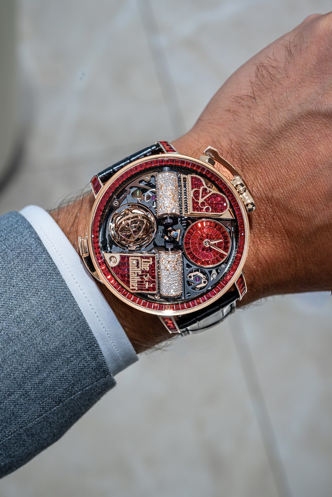 Front view of the red-sapphire Opera Godfather Baguette on a wrist with a grey jacket and white shirt cuff