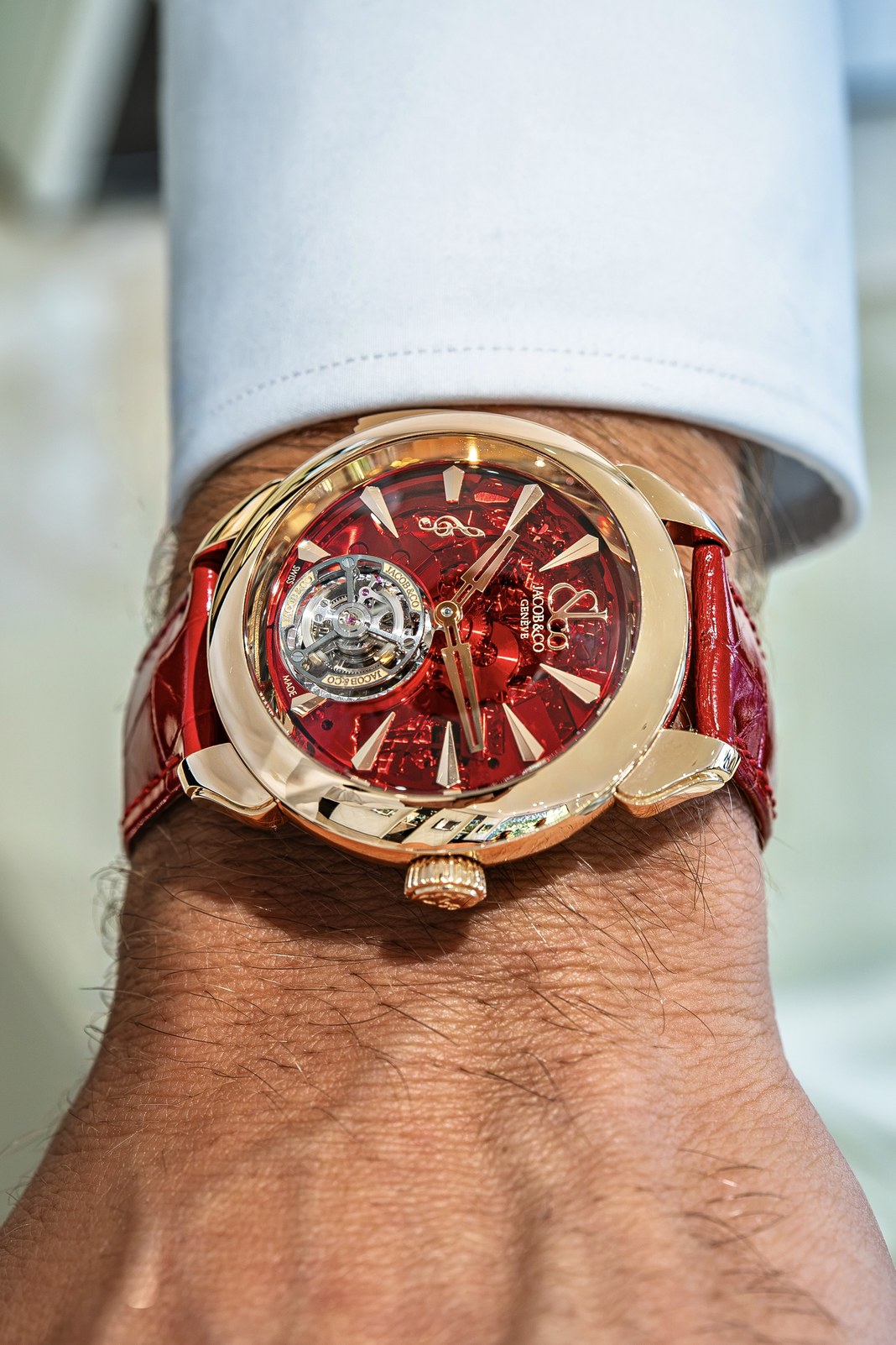 Close view of the red mineral-crystal dial, with gold hands, applied markers, a treble clef and an exposed tourbillon