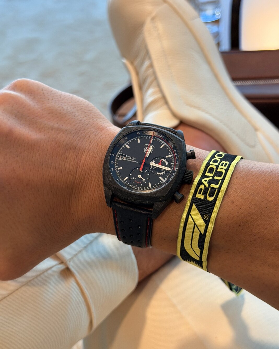 A TAG Heuer Monza with a dark, mottled case on a wrist in daylight, with the Formula 1 Paddock Club wristband
