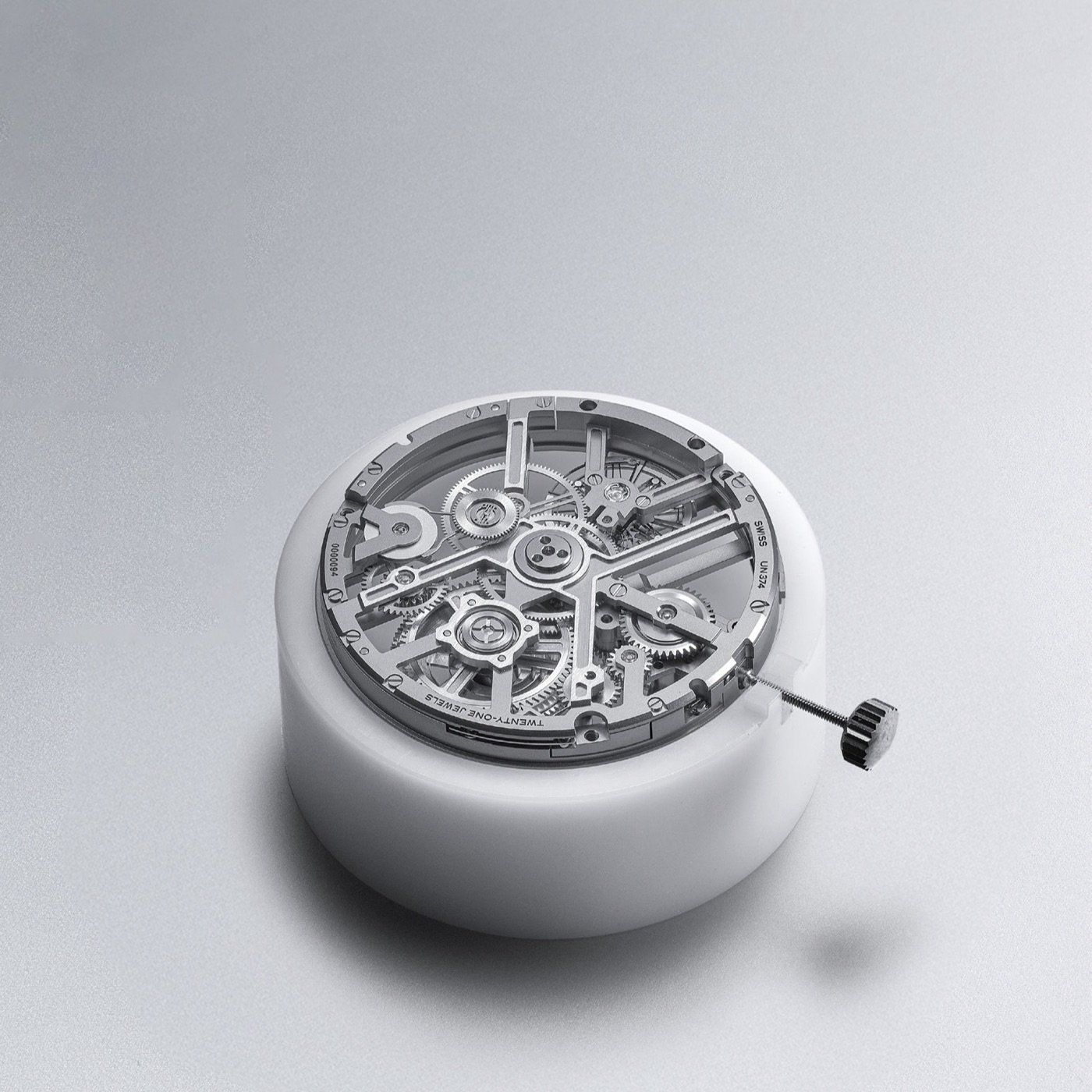 The bare UN-374 calibre resting on a white cylinder, winding crown still attached