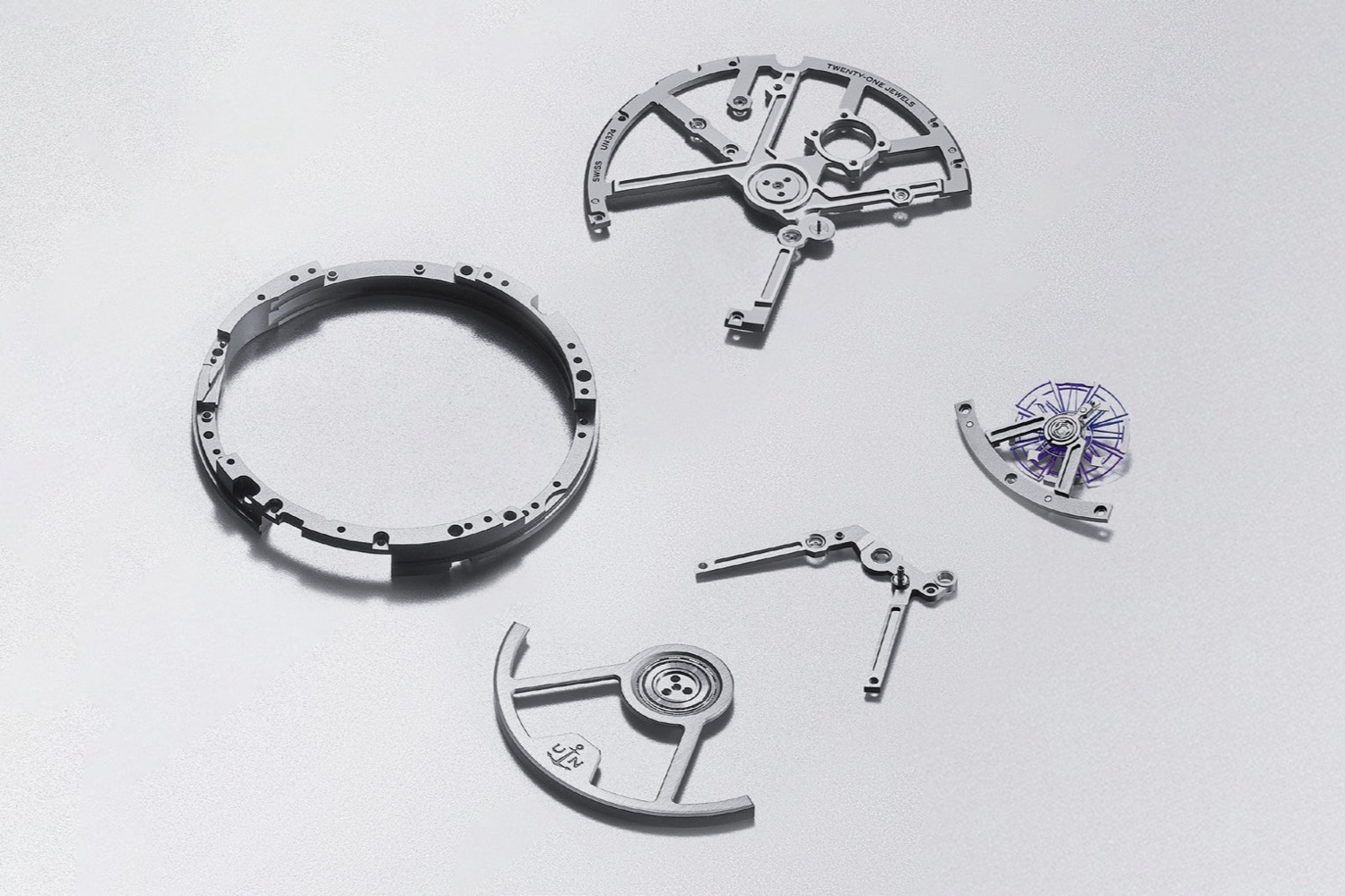 Disassembled parts of the Diver [AIR] laid flat: case ring, openworked bridges and the violet silicon escapement