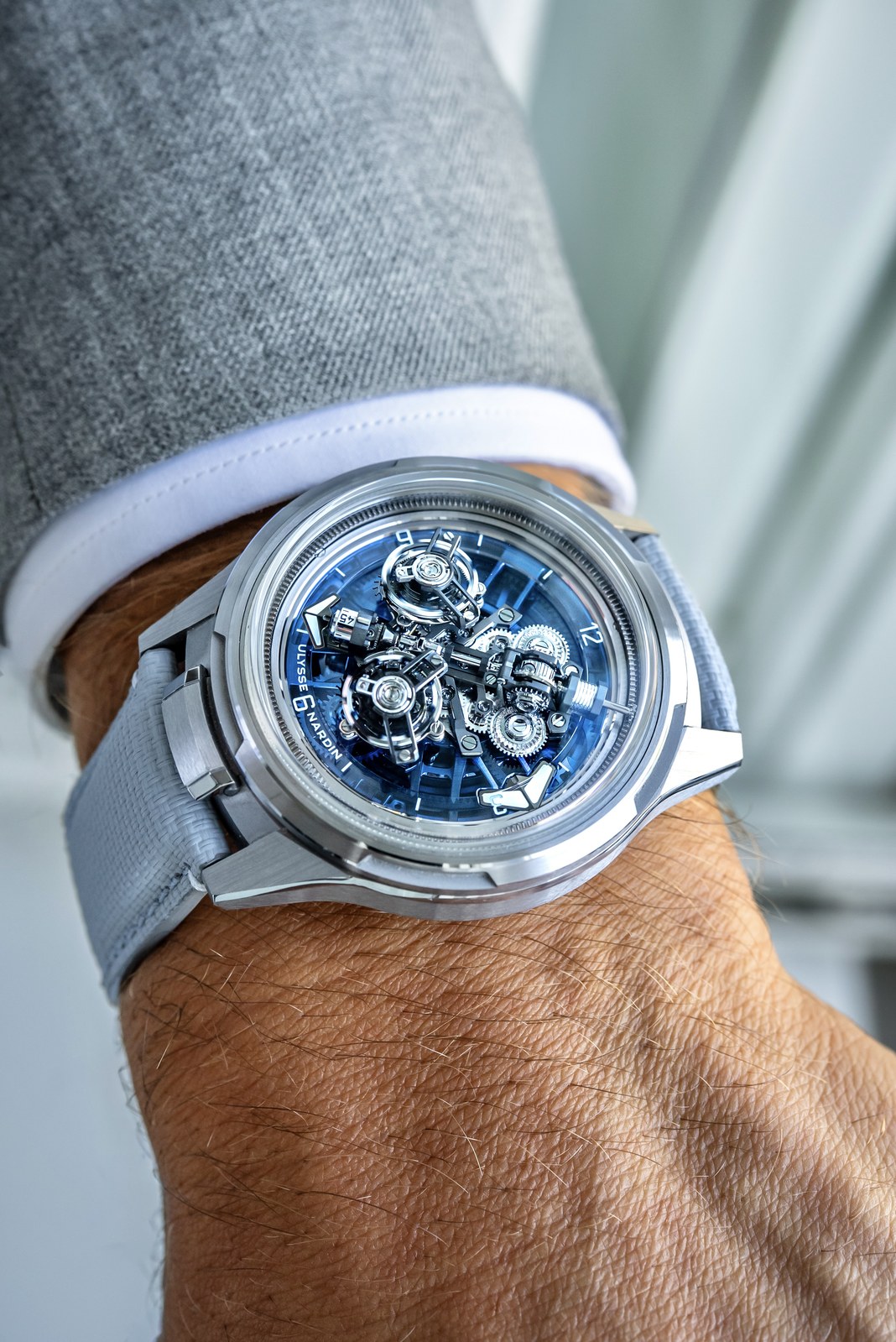 The Super Freak seen from the side on a wrist, with its crownless white-gold case, pale grey strap and open blue display