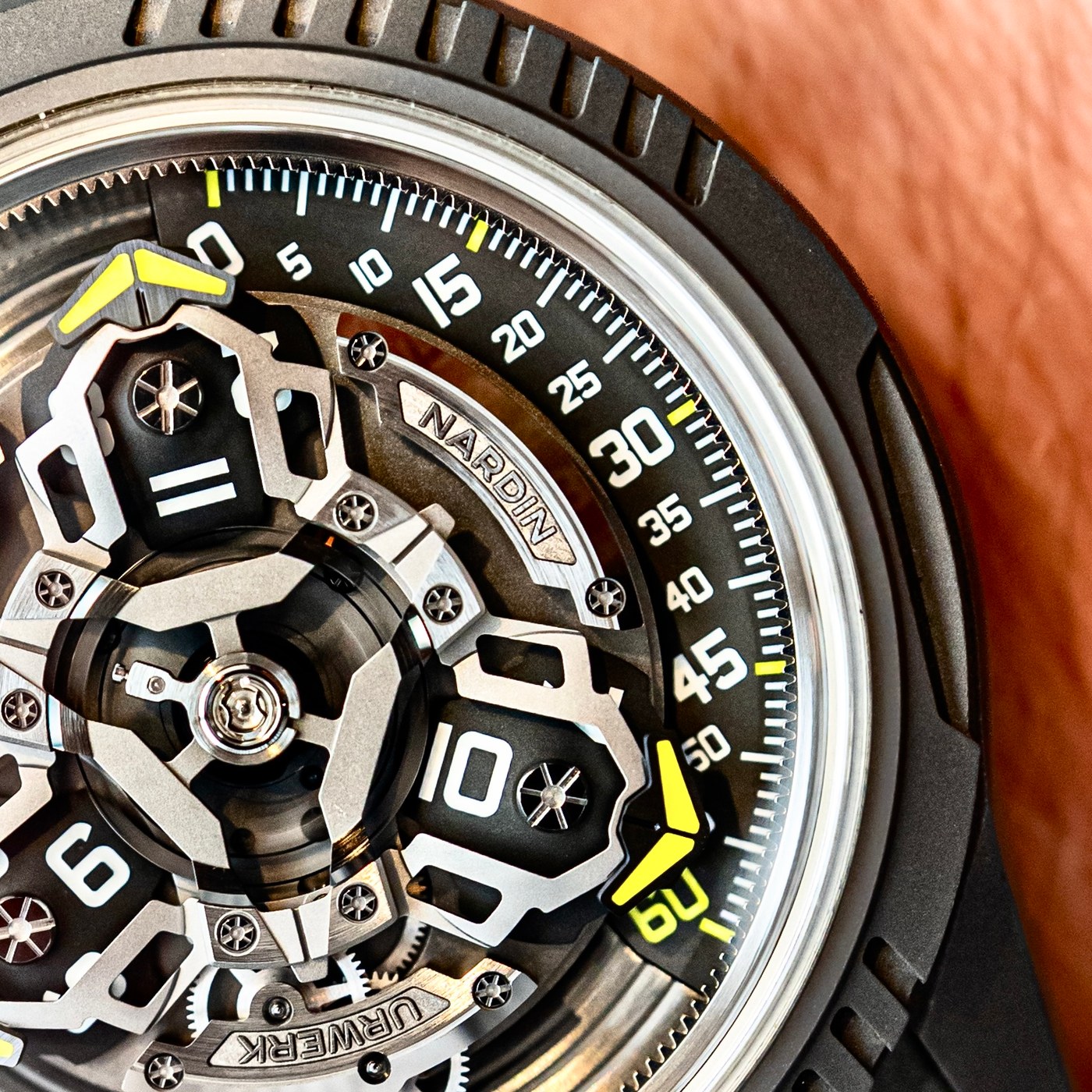 Close view of the UR-FREAK's carousel: three arms with domed hour discs, the silicon oscillator at the centre, the yellow pointer on the minute arc at the right