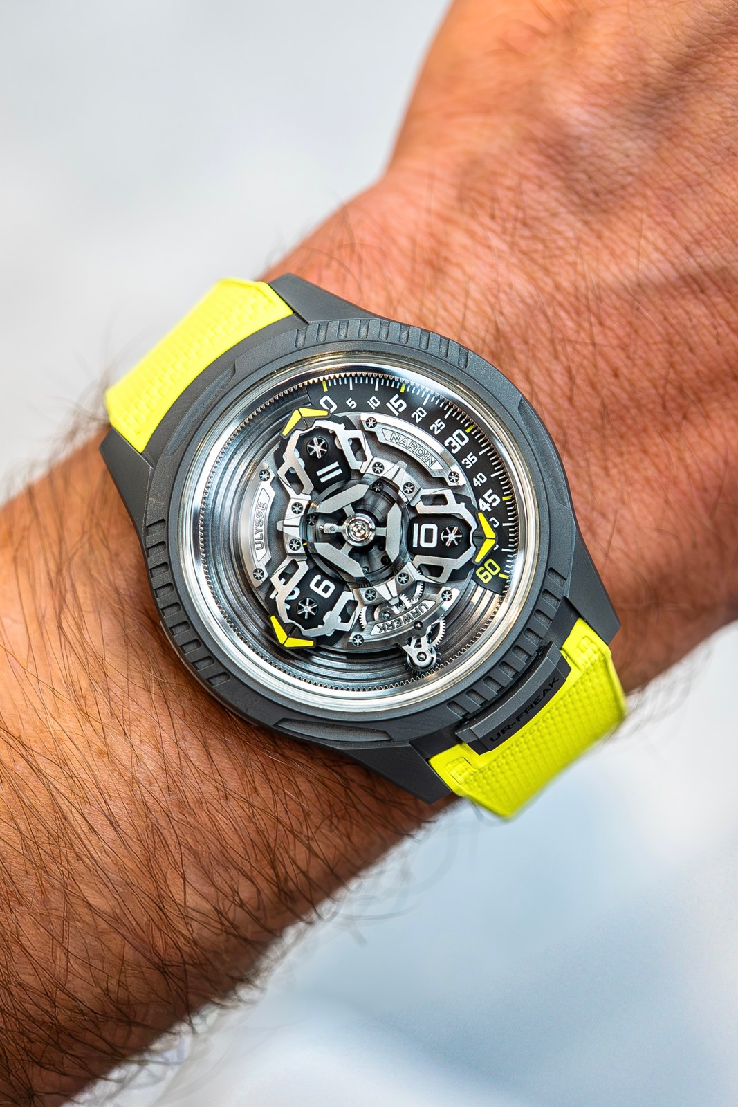 The UR-FREAK on a wrist, sandblasted grey titanium case and yellow textured rubber strap, the three satellite arms and the minute arc visible under the crystal