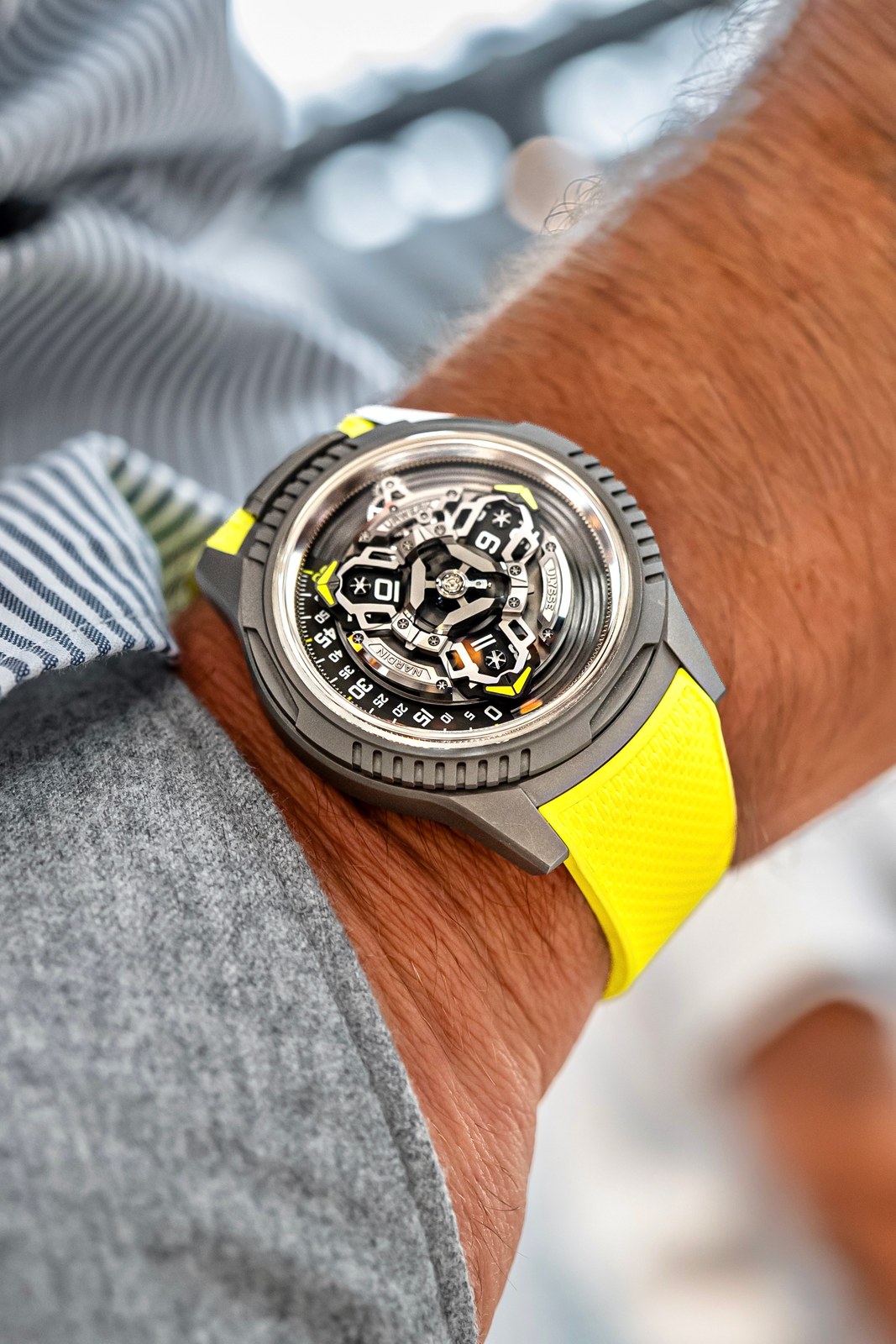 The UR-FREAK beside a striped shirt cuff, the yellow strap and the display with its minute arc showing